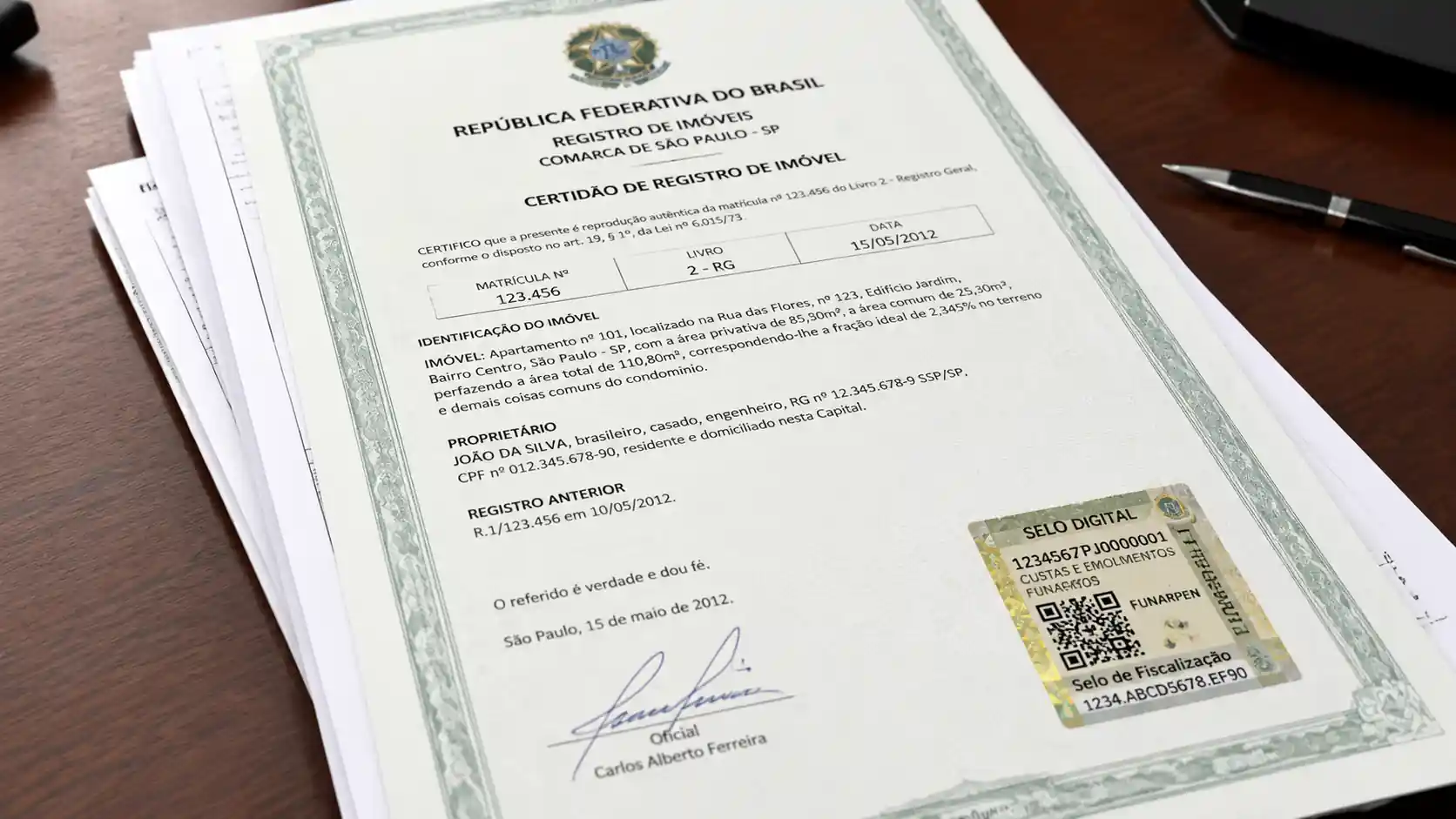 Documentos oficiais de registro de imóvel empilhados sobre mesa de cartório