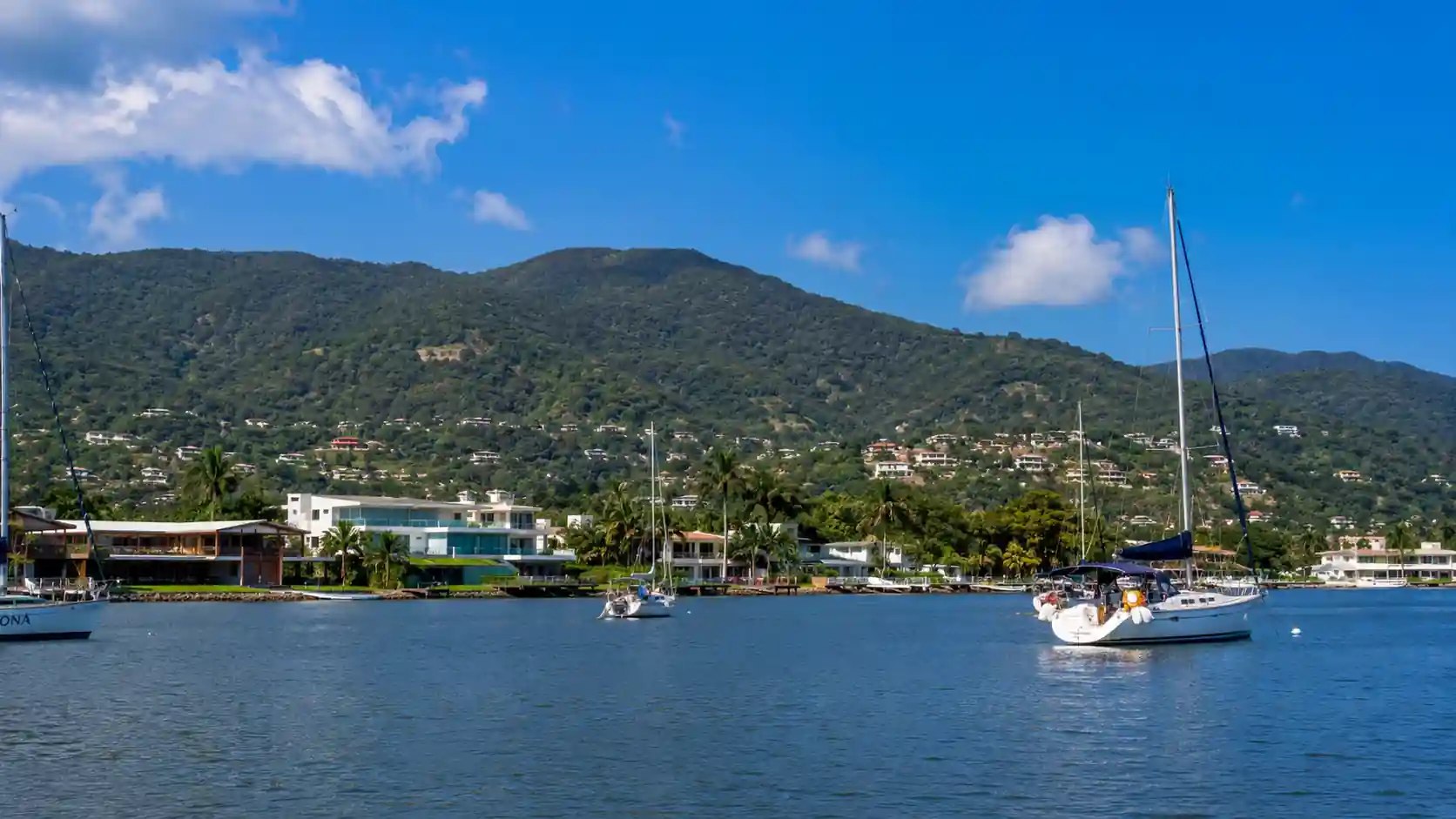 Lagoa da Conceição Florianópolis com barcos e morros ao redor em dia ensolarado