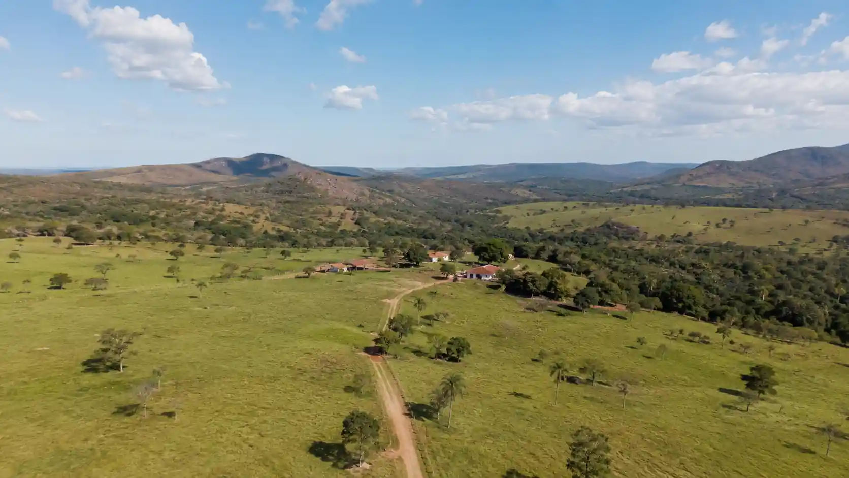 Fazenda brasileira com vegetação do Cerrado, colinas verdes e céu azul